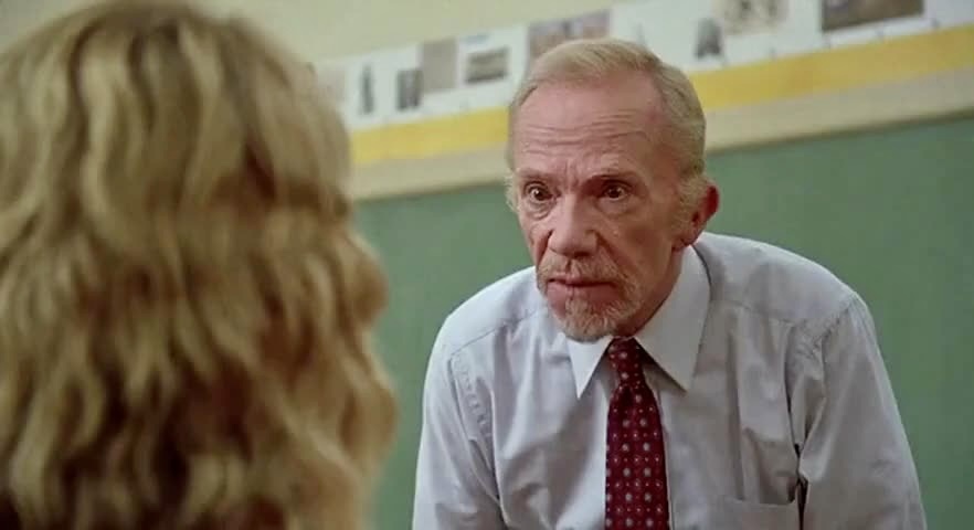 A person in a white shirt and red tie talking to a person
Description automatically generated